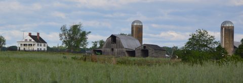 Farmhouse, barn and grain silos across an open field at the Auburn farmstead near Culpeper, Virginia