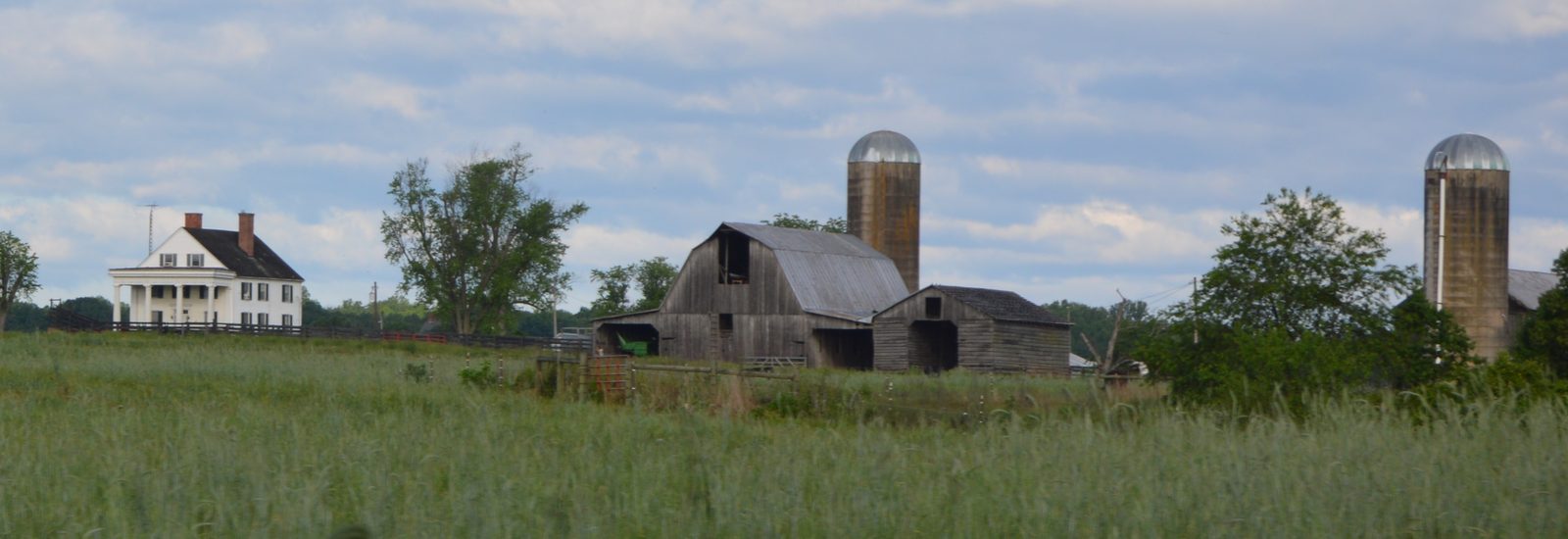 Farmhouse, barn and grain silos across an open field at the Auburn farmstead near Culpeper, Virginia