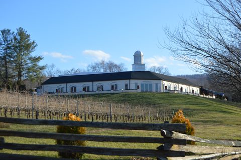 Winery building above vineyard rows and a timber fence at Barboursville, Orange County, Virginia